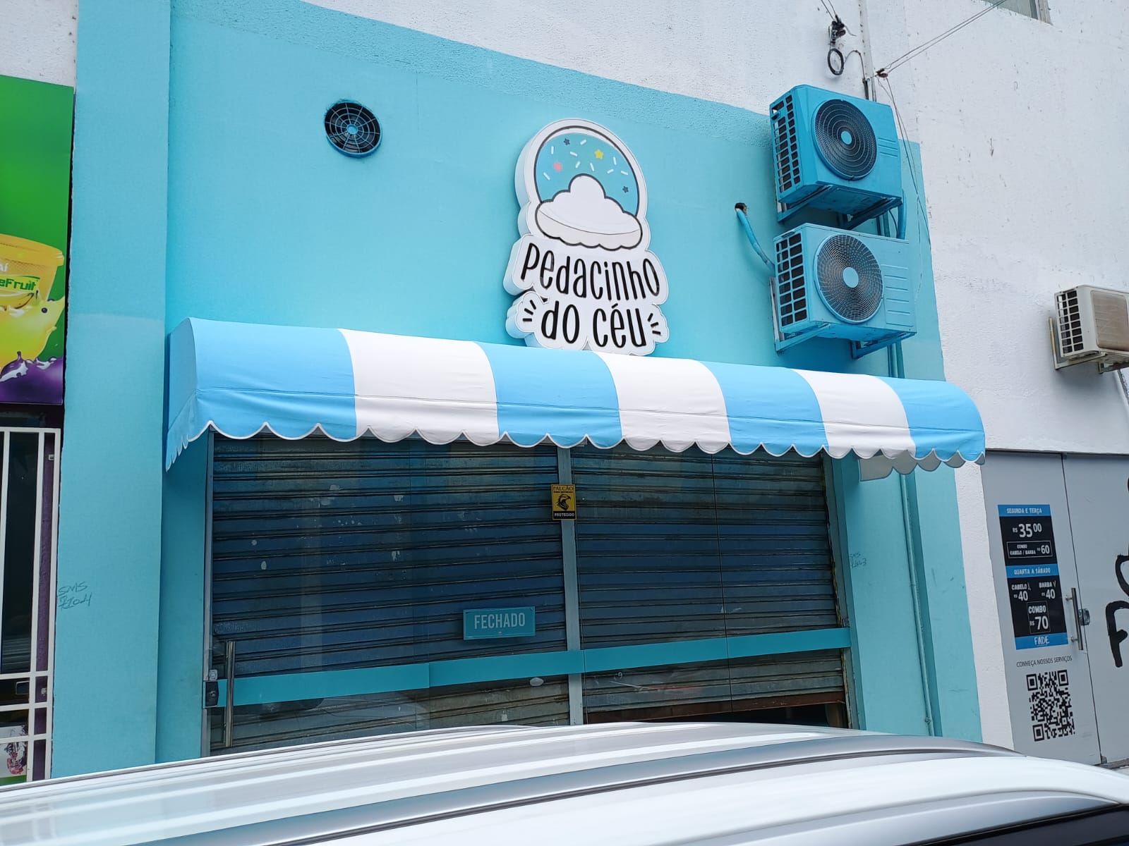 Toldo azul e branco instalado na fachada de um comércio